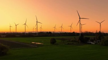 Günbatımında rüzgar türbinleri çiftliğinin havadan görüntüsü. Yenilenebilir enerji üretimi. Drone videosu.
