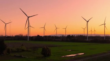 Günbatımında rüzgar türbinleri çiftliğinin havadan görüntüsü. Yenilenebilir enerji üretimi. Drone videosu.