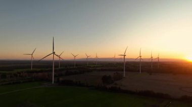Günbatımında rüzgar türbinleri çiftliğinin havadan görüntüsü. Yenilenebilir enerji üretimi. Drone videosu.