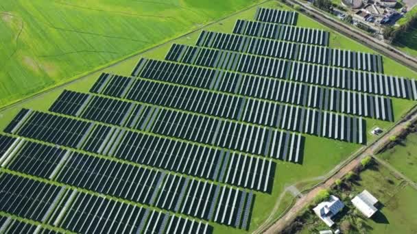 一个新的太阳能农场的俯瞰 绿地旁边的一排现代光伏太阳能电池板 — 图库视频影像