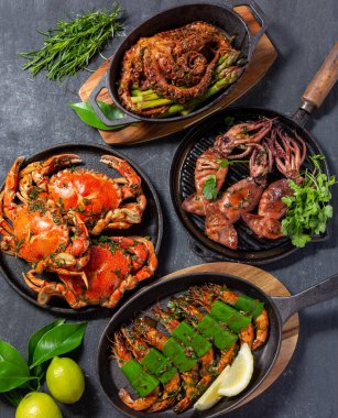 Deniz ürünleri tabağıyla sofra kurun. Pişmiş yengeç, kaplan karidesi, ızgara ahtapot ve dökme demir tavada mürekkep balığı.