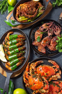 Deniz ürünleri tabağıyla sofra kurun. Pişmiş yengeç, kaplan karidesi, ızgara ahtapot ve dökme demir tavada mürekkep balığı.