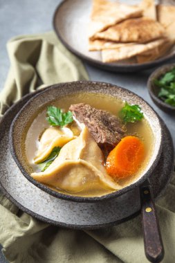 Geleneksel Yahudi Kreplach çorbası, et ve havuç, gri arka plan.