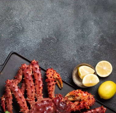 Canlı kral yengeci ve çeşitli limon dilimleri koyu, kırsal kayrak yüzey, kişniş, koyu dokulu arkaplan, kopyalama alanı, üst görünüm.