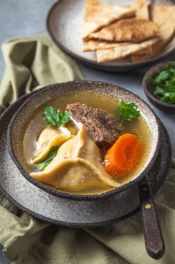 Geleneksel Yahudi Kreplach çorbası, et ve havuç, gri arka plan.