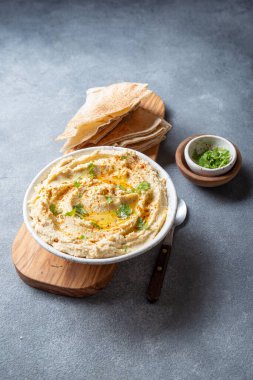 Zeytin yağı ve bitkilerle süslenmiş bir kase kremalı humus tahtadan yapılmış pide ekmeğiyle servis edilir. Ekmeğin yanına küçük bir kase garnitür yerleştirilir..