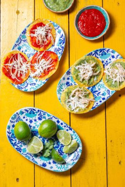 Cinco de Mayo ya da Dia de los Muertos gibi şenlikli Meksika etkinlikleri için mükemmel, güneşli sarı bir masa üzerinde süslü kireç süsleri içeren canlı tabaklarda servis edilen renkli chalupalar..