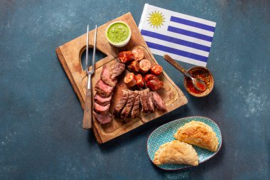 Aileler Uruguay 'daki şenlikleri kutlamak ve geleneksel bir asado' nun tadını çıkarmak için toplandılar. Izgara et, sosis ve börek ulusal bayrağın yanı sıra vatansever lezzetleri de sergiler..