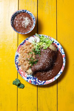 Bu canlı yemek enchiladas üzerine serpiştirilmiş mol poblano içerir, baharatlı pirinç ile süslenir ve marul, turp ve taze otlarla süslenir, bayram için mükemmel olur..