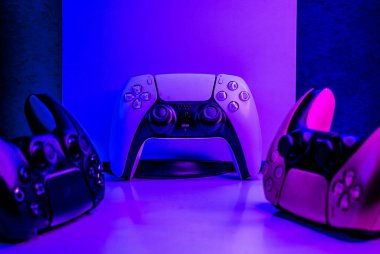 gaming joysticks on a table with console and neon lights, technology background, play with friends on playstation videogames with different gamepads, gamer background
