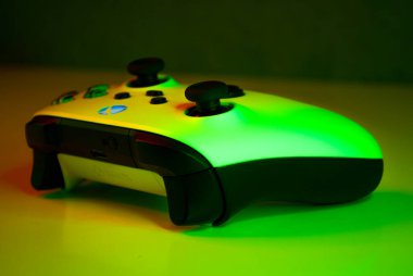 a closeup of a white xbox controller with a green screen background on the table