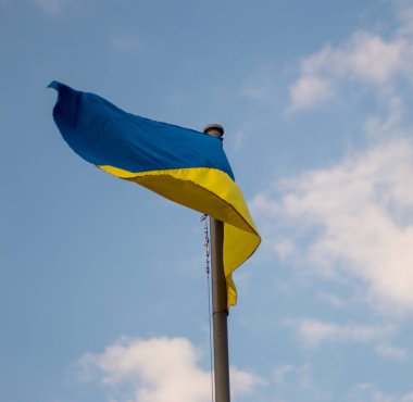 Mavi bir arkaplanda dalgalanan Ukrayna bayrağı.
