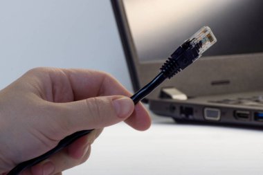 Adamın eli dizüstü bilgisayarı internet üzerinden Ian kablosuna bağlıyor.