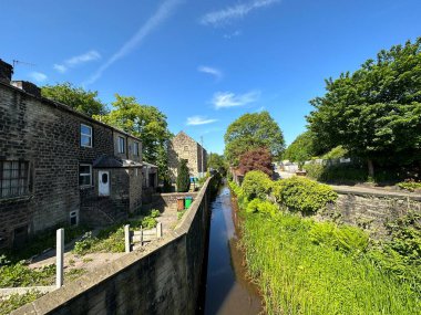 Viktorya döneminden kalma evlere yakın bir dere manzarası, bitkiler, ağaçlar, ve yakın mavi gökyüzü, Church Street Littleborough, İngiltere