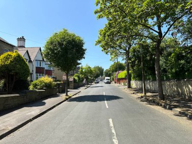 Grasmere Yolu, Huddersfield, İngiltere 'de bahçeler, eski ağaçlar ve mavi gökyüzü olan güzel bir yerleşim yeri manzarası.