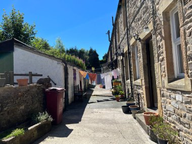 Gisburn, İngiltere 'de sıcak bir günde binaların, ağaçların ve çamaşır iplerinin olduğu arka sokağa bakın.