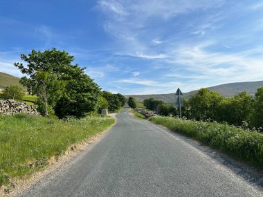 Beggarmans Yolu boyunca bakın, çimen kenarları, taş duvarlar, eski ağaçlar ve Hawes, İngiltere 'deki uzak tepeler. 