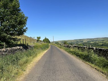 Blue Bell Yolu boyunca, kuru taş duvarlar, yabani bitkiler, ağaçlar ve tepeler ile güneşli bir günde, Ripponden, İngiltere