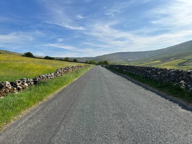 Beggarmans Yolu boyunca, kuru taş duvarlar, yabani bitkiler, tarlalar ve Hawes, İngiltere yakınlarındaki uzak tepeler manzaralı