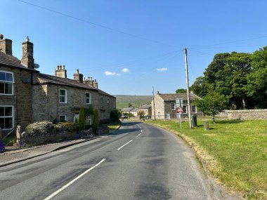 Bainbridge köyüne giden yol. Eski taş kulübeleri, çimen kenarları ve yakınlarındaki ağaçlarla. Leyburn, İngiltere.