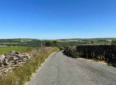Güneşli bir günde, Helm Lane, kuru taş duvarlar, yabani bitkiler, tarlalar ve ağaçlarla, Sowerby Köprüsü, İngiltere 
