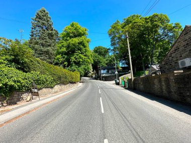 Otley Yolu, taş duvarlar, çalılar, eski ağaçlar ve taş evler, canlı mavi gökyüzüne karşı, İngiltere, Doğu Morton 'da.