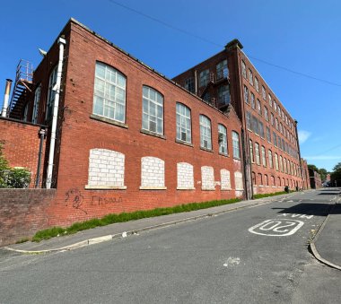 Güneşli bir günde, pencereleri tahta kaplı Viktorya dönemi kırmızı tuğla fabrikası, Burnley Brow, Oldham, İngiltere