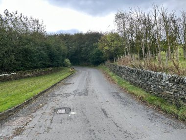 Pit Lane 'de yağmurlu bir hava var, kuru taş duvarlar, ağaçlar ve tarlalar var, Thornton, Bradford, İngiltere