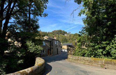 Kuzey Beck üzerinde uzanan antik taş köprüye bakın, gözlerinizi Goose Eye, Keighley, Yorkshire, İngiltere 'nin pitoresk köyüne yerleştirilmiş büyüleyici eski kulübelere yöneltin..