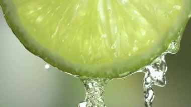 Yeşil Arkaplanda Limon Kesiği 'nden Süper Yavaş Makro Akan Su Çekimi. Yüksek kalite 4k görüntü