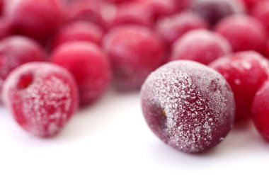 Yüzeyinde buz kristalleri olan donmuş kirazların beyaz arka planda izole edilmiş makro görüntüsü..