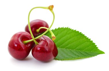 Beyaz arka planda yeşil yapraklı üç olgun kiraz, sulu kırmızı meyveleri yakından görmek, yaz hasadı kavramı, sağlıklı beslenme ve organik gıda.