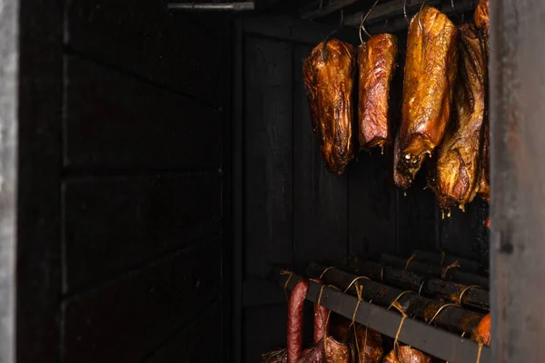 Close up of smoked meat and belly or beech meat with dark crust in a smokehouse or smoker, food concept
