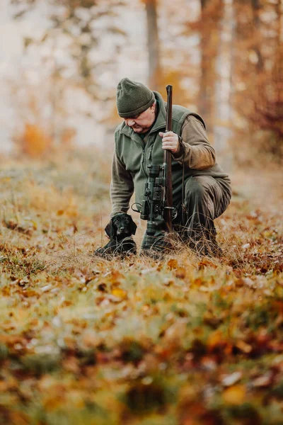 Hunter or ranger with gun or rifle with a dog in a forest hunting of some venison, hunting period, autumn season, hunting and people concept