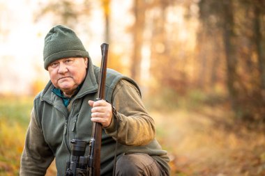 Portrait of hunter or ranger with a hunting gun and hunting form to hunt in an autumn forest, hunting concept
