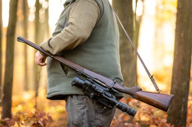 Hunter or ranger with a professional, nightvision hunting gun and hunting form to hunt in an autumn forest, hunting concept
