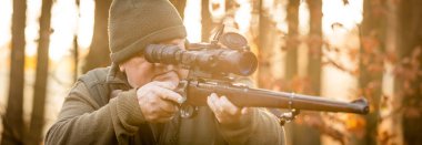 Profesyonel bir avcı ya da korucu, gece görüşlü av tüfeği ile sonbahar ormanlarında avlanmak için vahşi hayvan ve avlanma biçimi hedefliyor.