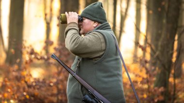 Sonbahar av sezonu, tüfekli avcı ormanda ya da ormanda vahşi bir hayvanı arıyor, açık hava sporları konsepti.