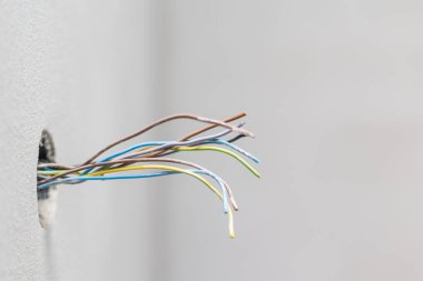 Open electric plug at home with kind of seen cables, electrical wires, wiring, socket on an old concrete building wall