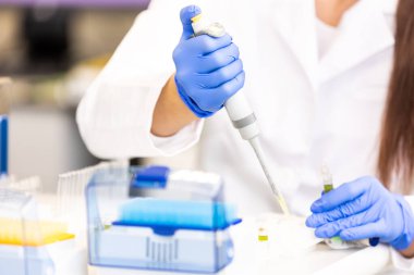 Genç bir bilim adamı ya da tıp teknisyeni klinik laboratuarında cam şişede yeni eczacılık ilaçları geliştiriyor.