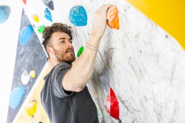 Genç adam tebeşirli ellerle duvarlara tırmanıyor.