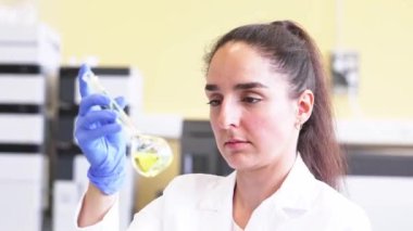 Genç bilim adamı ya da tıbbi teknisyen cam şişede yeni eczane ilaçları geliştiriyor. Klinik bir laboratuvarda, ilaç araştırmaları ve araştırma konseptinde.