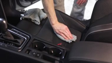 Araba temizleme konsepti, genç adam araba koltuklarını paçavra ve fırçayla temizleme, araba bakımı.