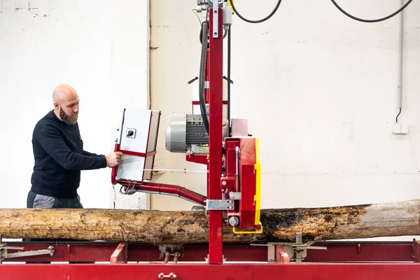 stock image Professional carpenter cutting raw wood on a table with electric band saw, cutting wooden board at sawmill, carpentry manufacturing concept