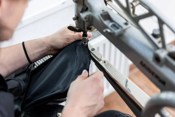 Black leather bag repair in tailoring studio, leatherworking concept