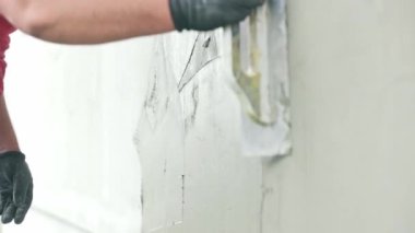 Genç bir işçi evin dış cephesine yapıştırıcı ya da yapıştırıcı sürerek evin yalıtımını yapıyor.