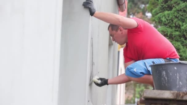 男工用胶水或胶粘剂涂在房屋的正面 房屋的绝缘上 — 图库视频影像