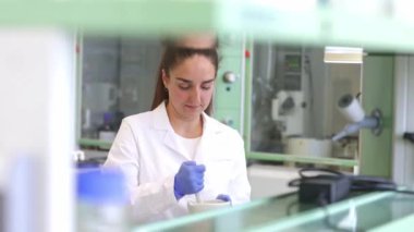 Genç bilim adamı ya da araştırmacı kadın modern laboratuarda, endüstriyel konseptte yeni bir biyolojik, ekolojik kozmetik ürünü geliştiriyor.