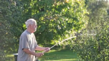 Kurak mevsimde bahçeyi sulayan kıdemli adam, bahçıvanlık konsepti.