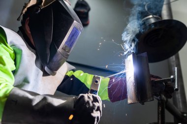 Sanayi işçisi bir fabrikada metal kaynak yapıyor, kaynak kavramı.